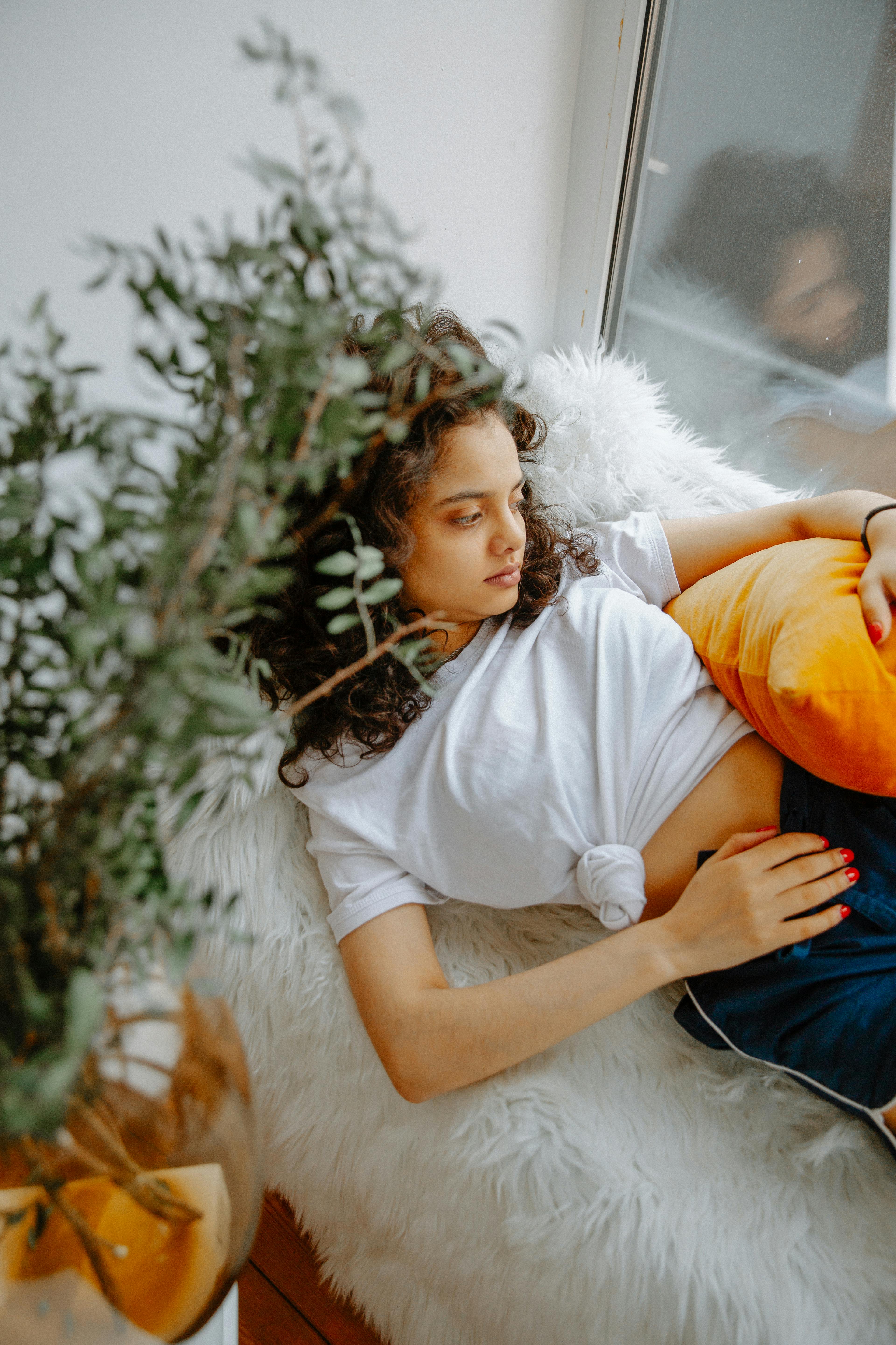 Teenager resting on a cozy couch with a pillow, experiencing menstrual discomfort.